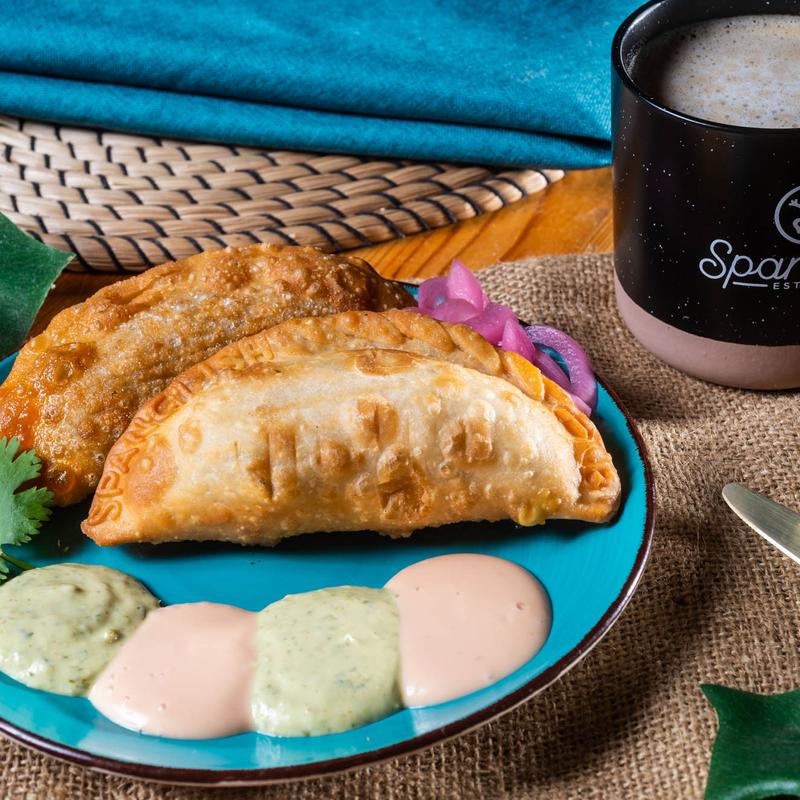 Koki empanadas on a turquoise plate with dipping sauces